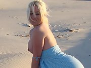 Blonde bombshell shows off her tattoos at the sandy beach