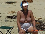 Mature blonde wife sits outside naked sun bathing in her yard